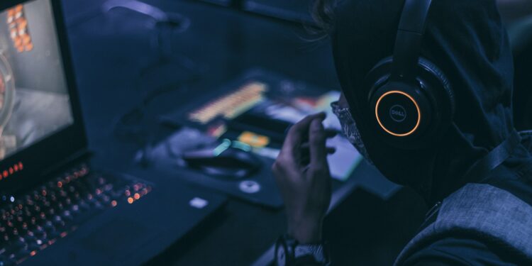 A gamer wearing headphones is deeply immersed in a gaming session on a high-performance laptop, showcasing the latest in gaming technology.